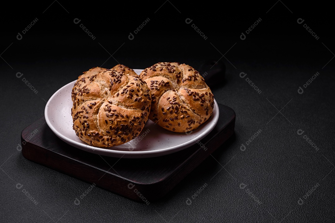Delicioso pão crocante fresco assado com sementes e grãos sobre um fundo escuro de concreto