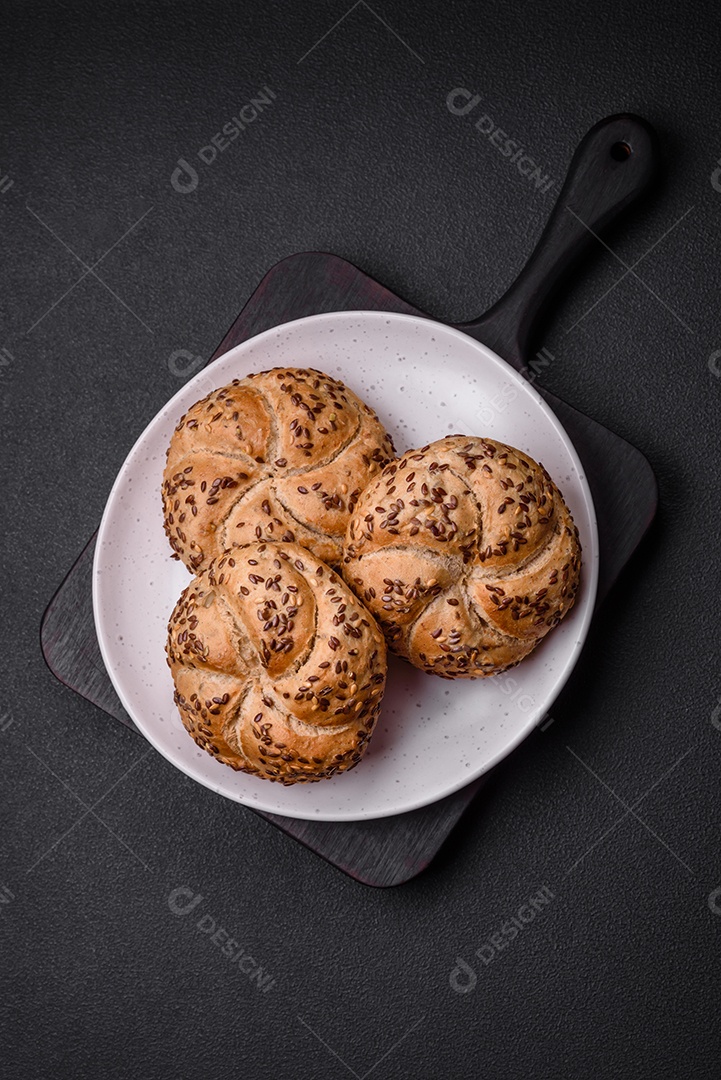 Delicioso pão crocante fresco assado com sementes e grãos sobre um fundo escuro de concreto