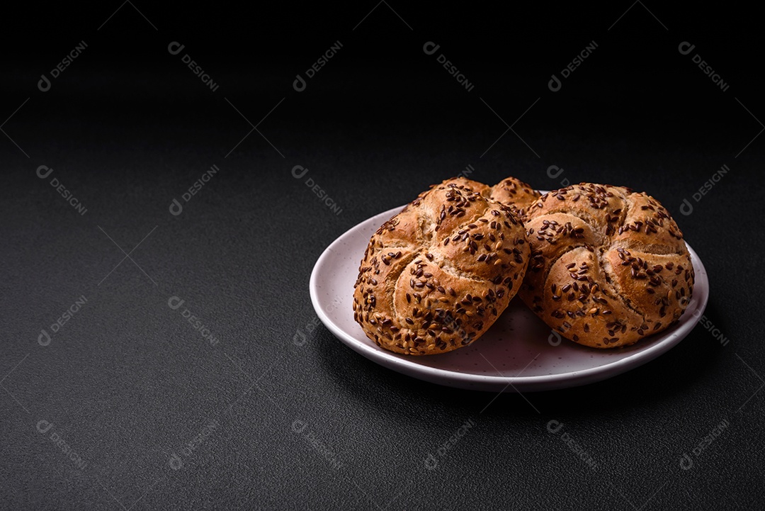 Delicioso pão crocante fresco assado com sementes e grãos sobre um fundo escuro de concreto