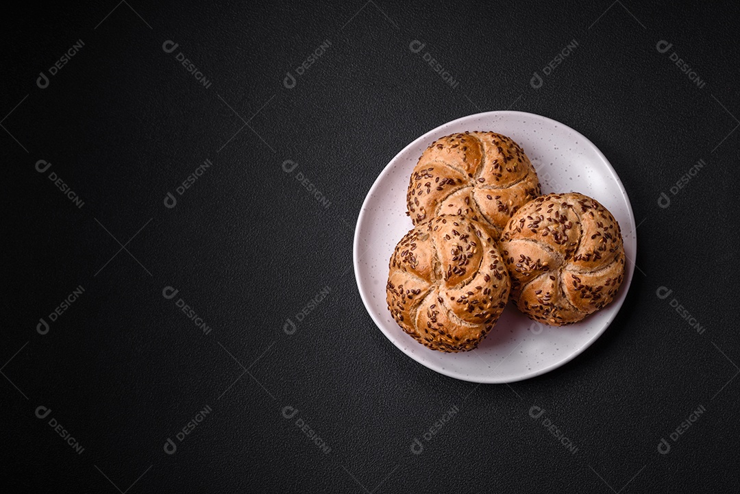 Delicioso pão crocante fresco assado com sementes e grãos sobre um fundo escuro de concreto
