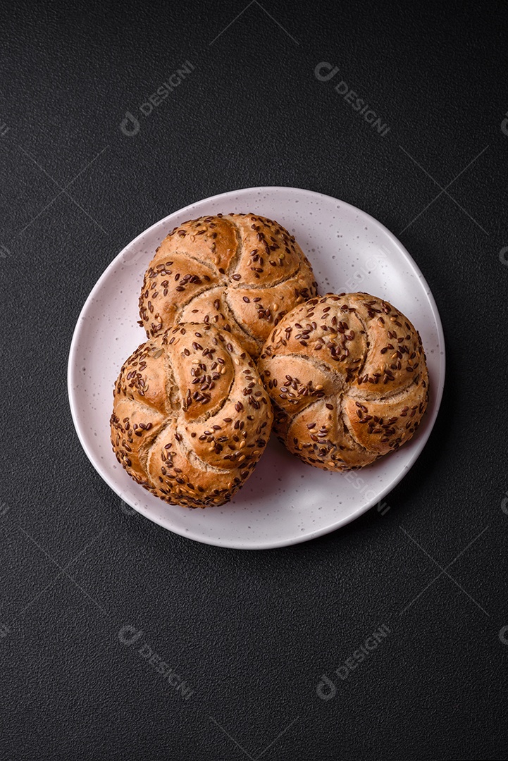 Delicioso pão crocante fresco assado com sementes e grãos sobre um fundo escuro de concreto