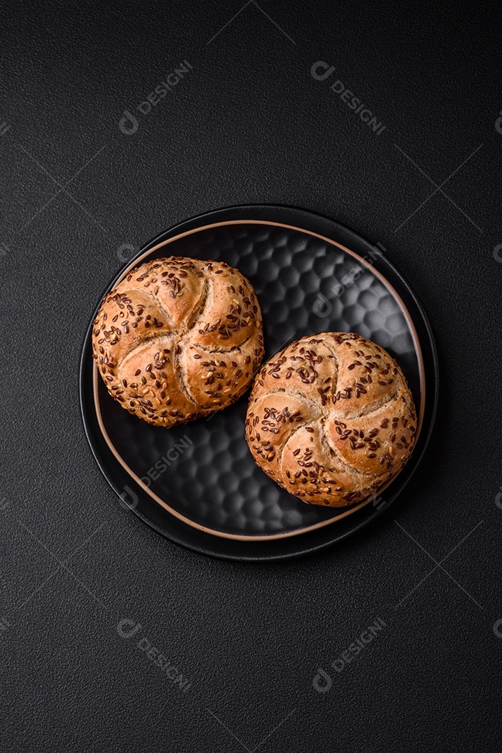 Delicioso pão crocante fresco assado com sementes e grãos sobre um fundo escuro de concreto