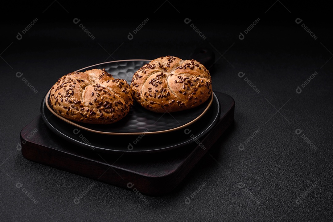 Delicioso pão crocante fresco assado com sementes e grãos sobre um fundo escuro de concreto