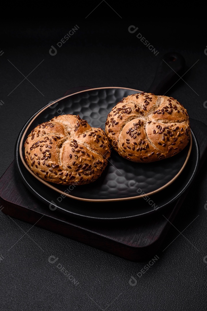 Delicioso pão crocante fresco assado com sementes e grãos sobre um fundo escuro de concreto