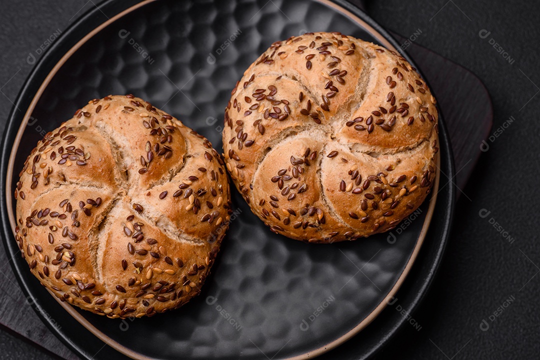 Delicioso pão crocante fresco assado com sementes e grãos sobre um fundo escuro de concreto