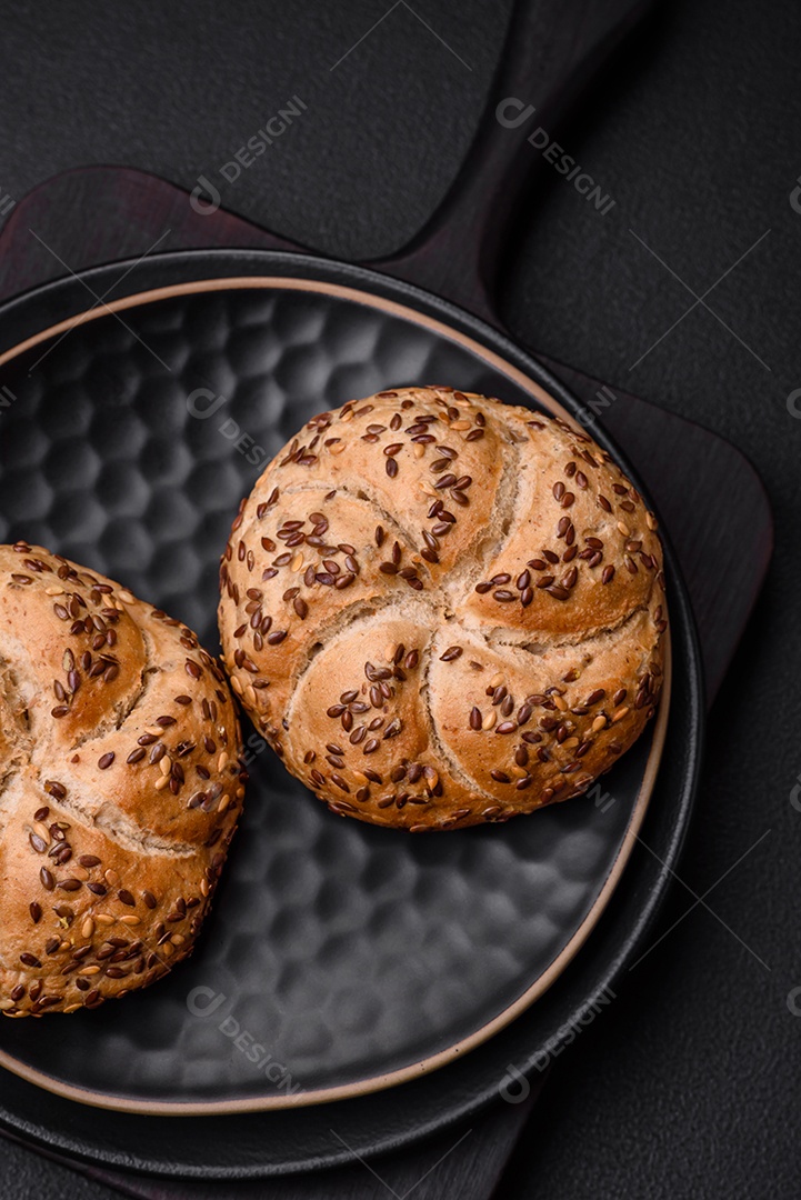 Delicioso pão crocante fresco assado com sementes e grãos sobre um fundo escuro de concreto