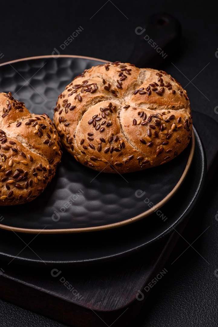 Delicioso pão crocante fresco assado com sementes e grãos sobre um fundo escuro de concreto