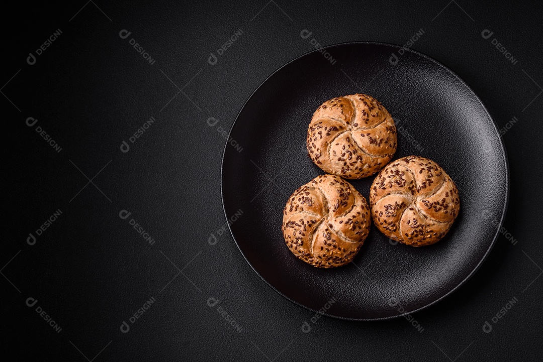 Delicioso pão crocante fresco assado com sementes e grãos sobre um fundo escuro de concreto