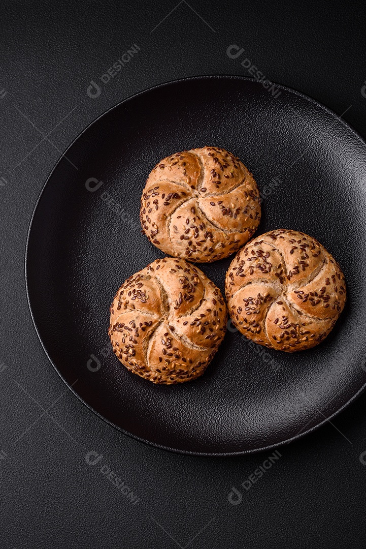 Delicioso pão crocante fresco assado com sementes e grãos sobre um fundo escuro de concreto