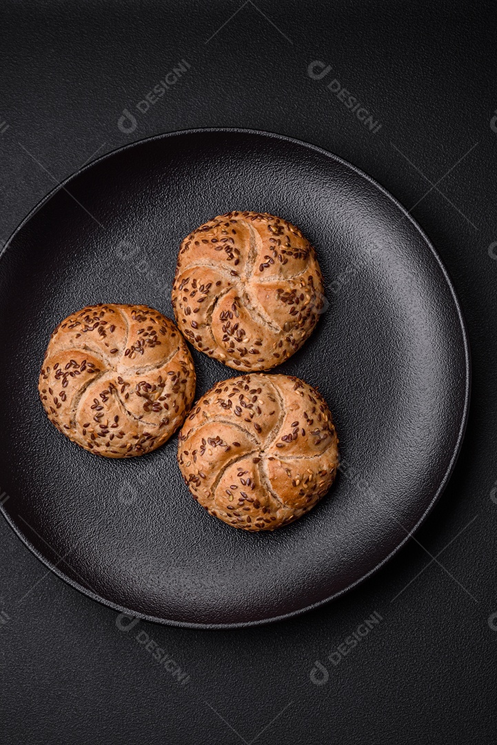 Delicioso pão crocante fresco assado com sementes e grãos sobre um fundo escuro de concreto