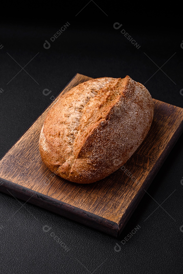 Delicioso pão crocante fresco assado com sementes e grãos sobre um fundo escuro de concreto