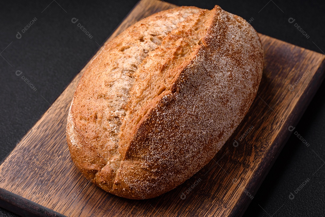 Delicioso pão crocante fresco assado com sementes e grãos sobre um fundo escuro de concreto