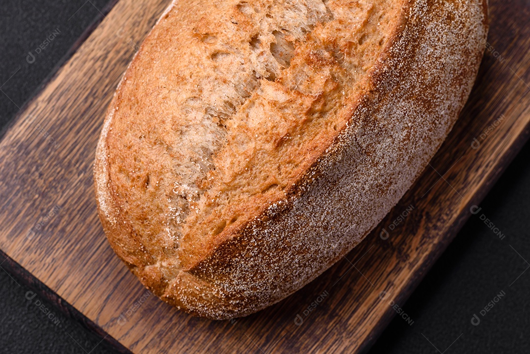 Delicioso pão crocante fresco assado com sementes e grãos sobre um fundo escuro de concreto