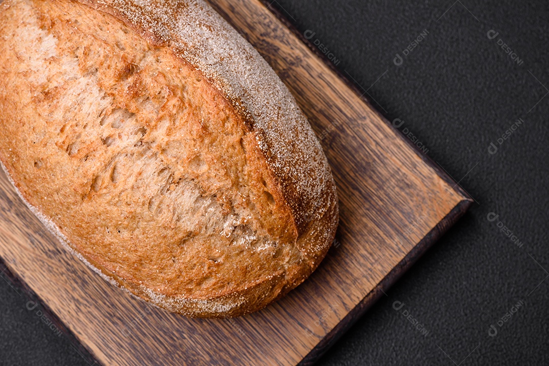 Delicioso pão crocante fresco assado com sementes e grãos sobre um fundo escuro de concreto