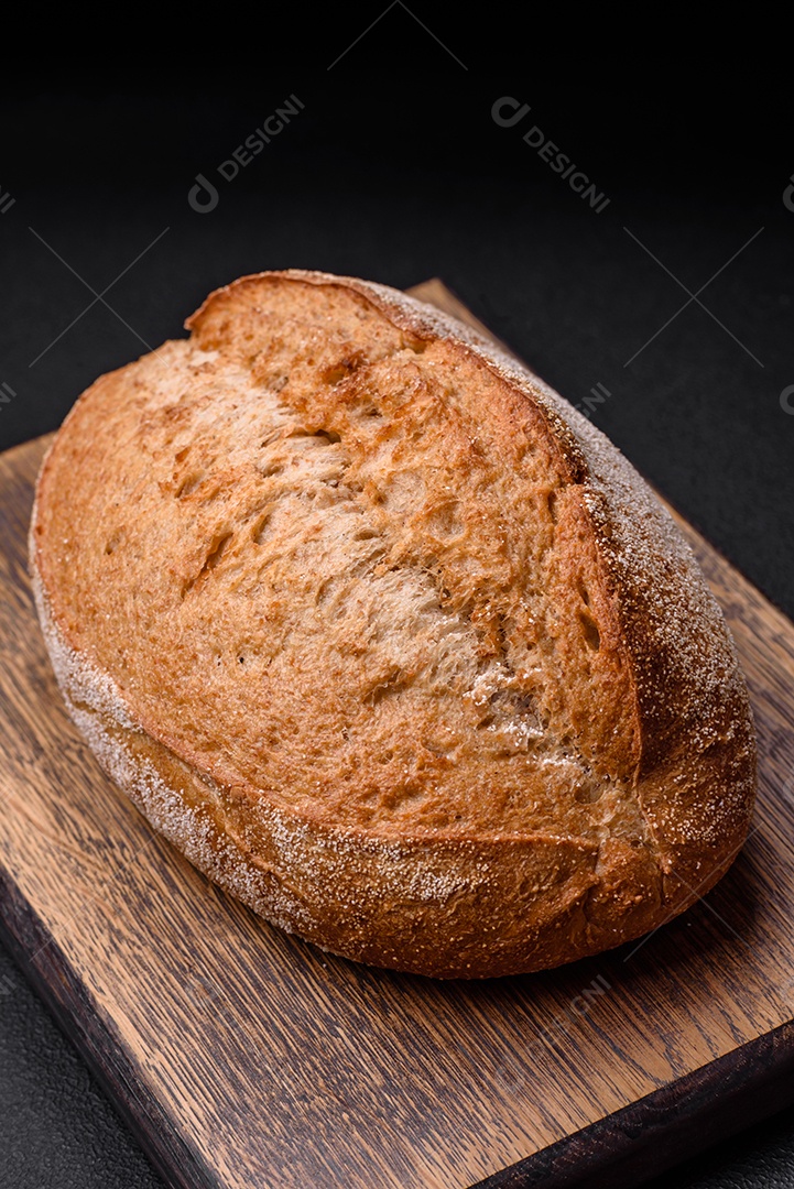 Delicioso pão crocante fresco assado com sementes e grãos sobre um fundo escuro de concreto