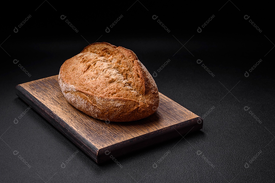 Delicioso pão crocante fresco assado com sementes e grãos sobre um fundo escuro de concreto