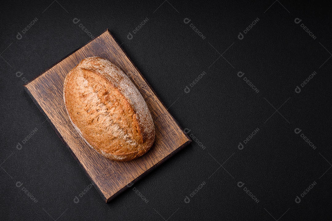 Delicioso pão crocante fresco assado com sementes e grãos sobre um fundo escuro de concreto