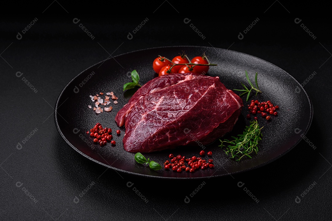 Carne crua suculenta com especiarias, sal e ervas sobre um fundo escuro de concreto. Preparando-se para cozinhar um prato de carne