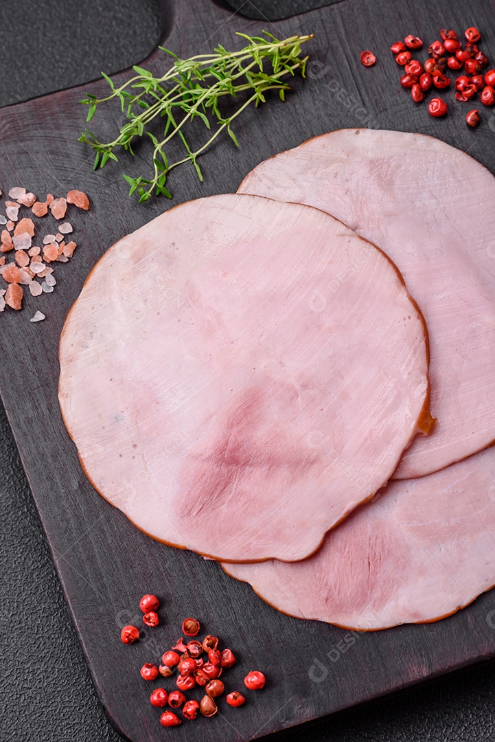 Delicioso presunto fresco cortado em fatias redondas com sal, especiarias e ervas sobre fundo escuro de concreto