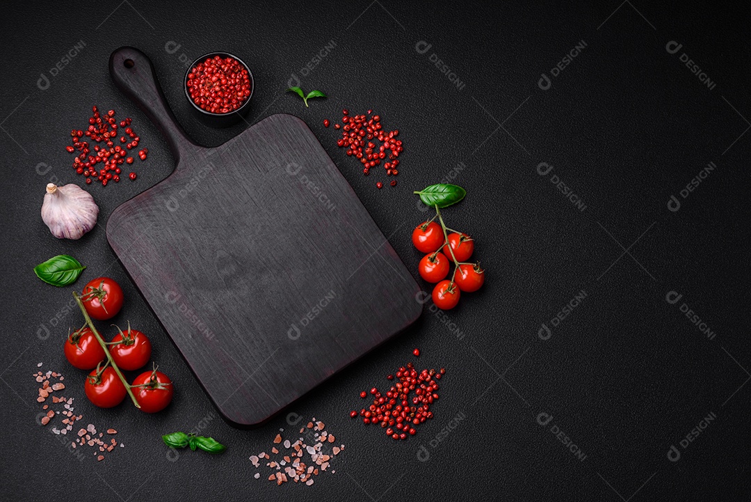 Ingredientes para cozinhar tomate cereja, sal, especiarias e ervas sobre um fundo escuro de concreto