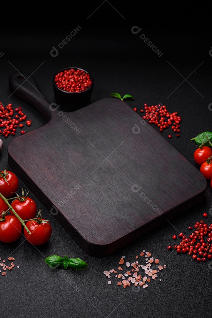 Ingredientes para cozinhar tomate cereja, sal, especiarias e ervas sobre um fundo escuro de concreto