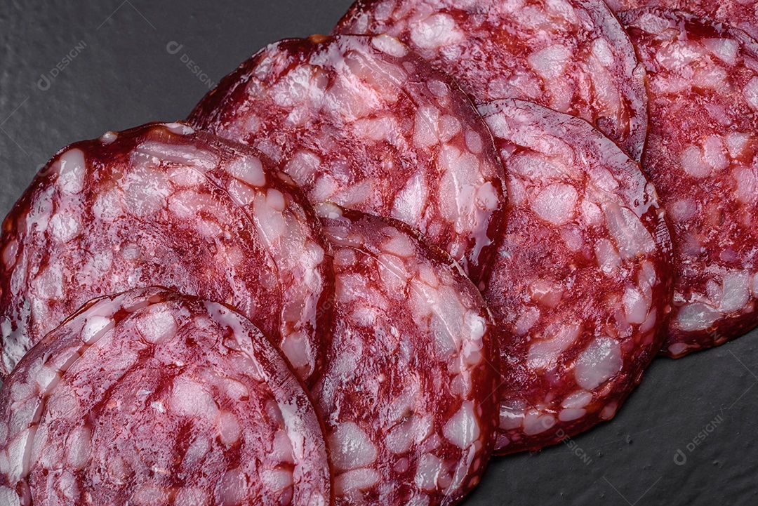 Deliciosa linguiça defumada com bacon, sal, especiarias e ervas cortadas em fatias sobre uma tábua de madeira