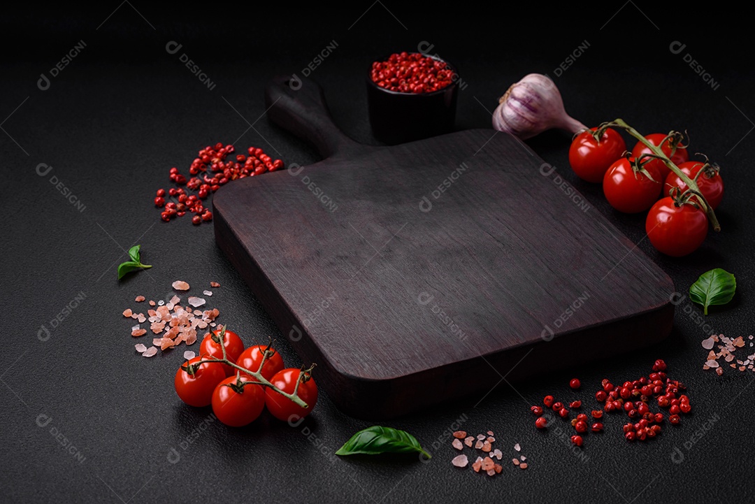 Ingredientes para cozinhar tomate cereja, sal, especiarias e ervas sobre um fundo escuro de concreto