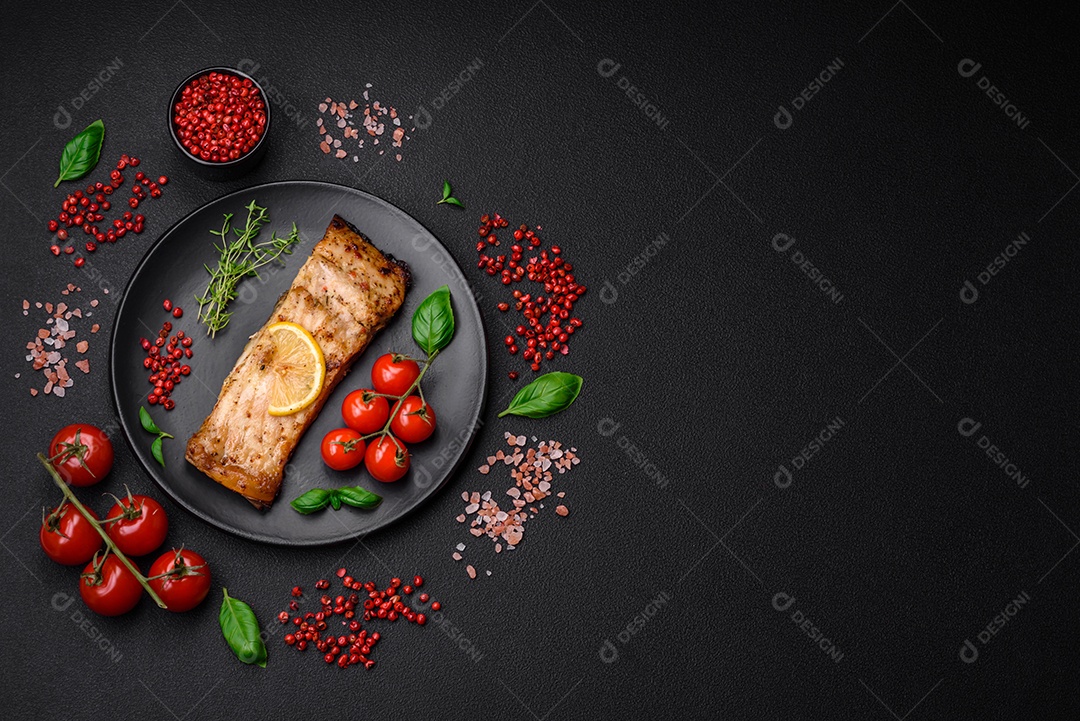 Fatia de delicioso peixe assado com sal, especiarias e ervas em uma placa cerâmica sobre um fundo escuro de concreto
