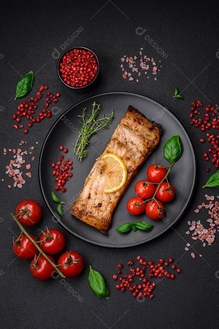 Fatia de delicioso peixe assado com sal, especiarias e ervas em uma placa cerâmica sobre um fundo escuro de concreto