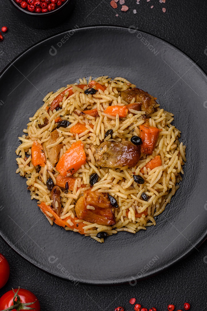 Delicioso pilaf fresco com arroz, cenoura, carne, cebola, especiarias e bagas num prato cerâmico sobre um fundo escuro de concreto