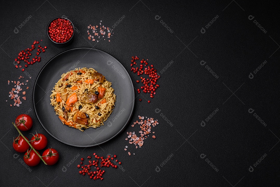 Delicioso pilaf fresco com arroz, cenoura, carne, cebola, especiarias e bagas num prato cerâmico sobre um fundo escuro de concreto