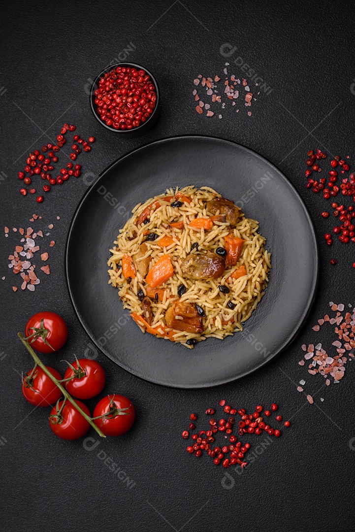Delicioso pilaf fresco com arroz, cenoura, carne, cebola, especiarias e bagas num prato cerâmico sobre um fundo escuro de concreto