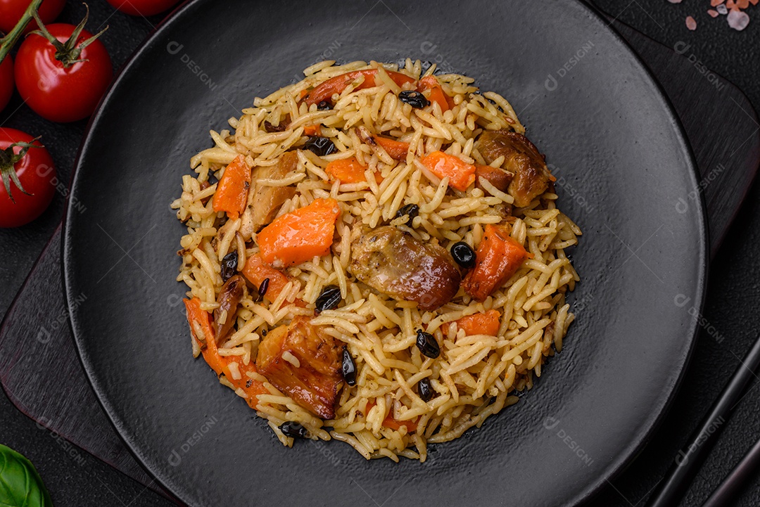 Delicioso pilaf fresco com arroz, cenoura, carne, cebola, especiarias e bagas num prato cerâmico sobre um fundo escuro de concreto