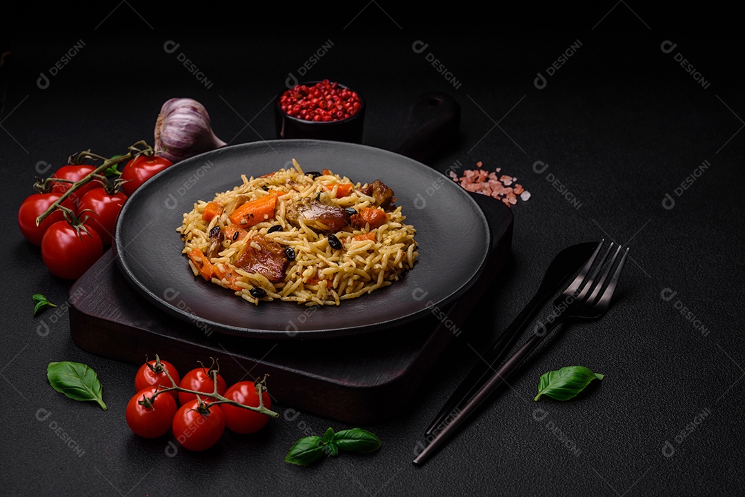 Delicioso pilaf fresco com arroz, cenoura, carne, cebola, especiarias e bagas num prato cerâmico sobre um fundo escuro de concreto