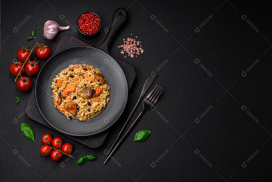 Delicioso pilaf fresco com arroz, cenoura, carne, cebola, especiarias e bagas num prato cerâmico sobre um fundo escuro de concreto