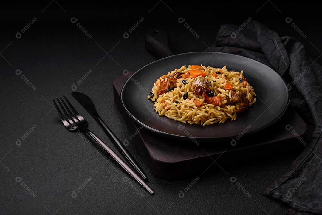 Delicioso pilaf fresco com arroz, cenoura, carne, cebola, especiarias e bagas num prato cerâmico sobre um fundo escuro de concreto