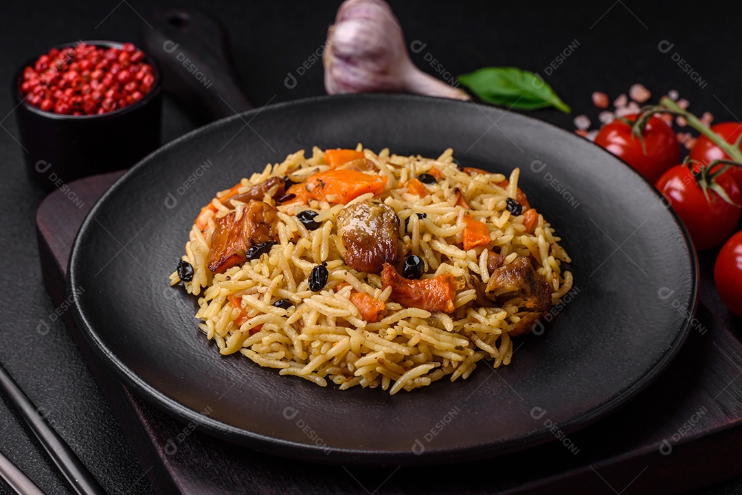 Delicioso pilaf fresco com arroz, cenoura, carne, cebola, especiarias e bagas num prato cerâmico sobre um fundo escuro de concreto