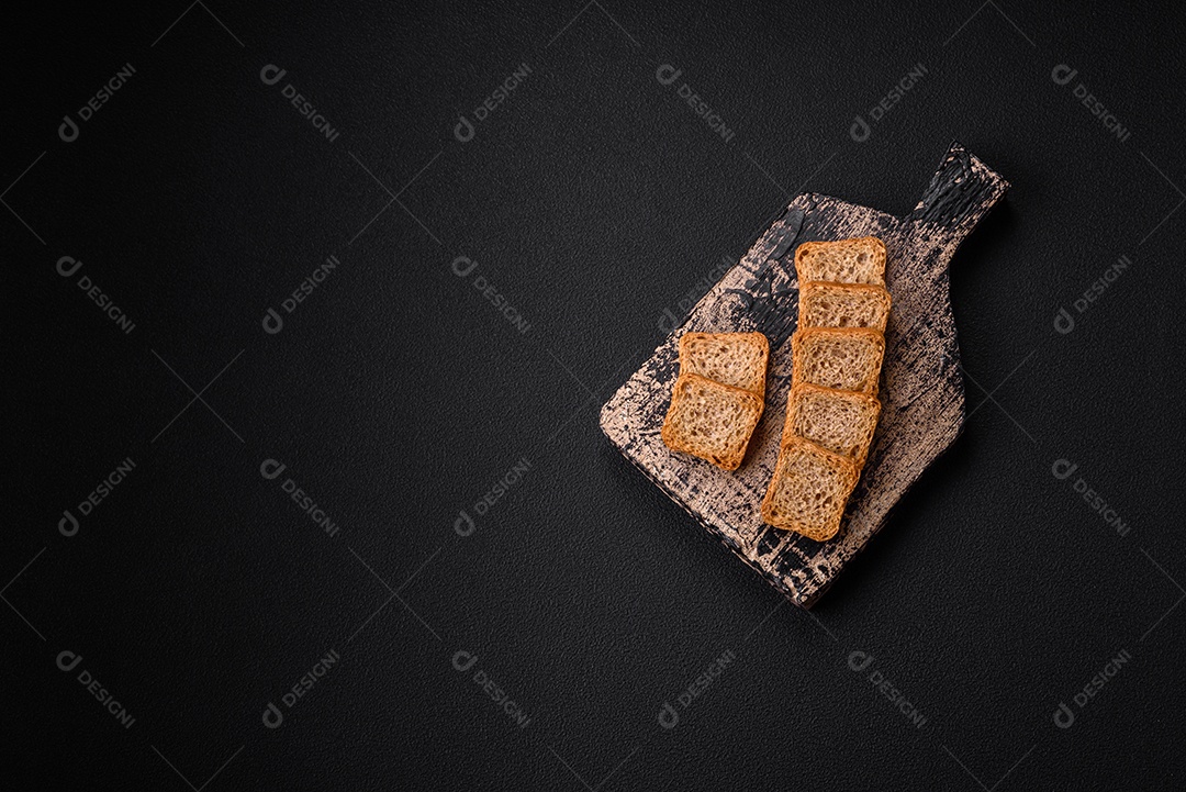 Deliciosos croutons de trigo retangulares salgados com sal e especiarias sobre um fundo escuro de concreto