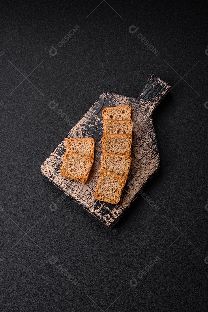 Deliciosos croutons de trigo retangulares salgados com sal e especiarias sobre um fundo escuro de concreto