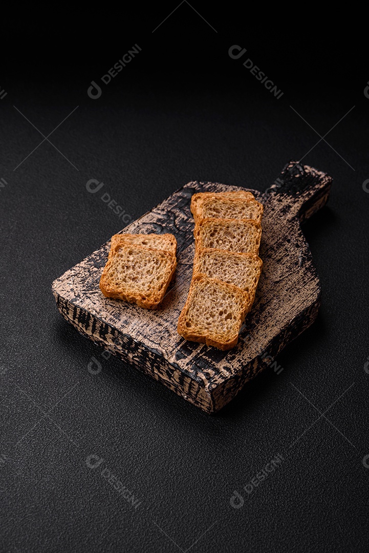 Deliciosos croutons de trigo retangulares salgados com sal e especiarias sobre um fundo escuro de concreto