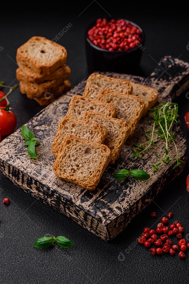 Deliciosos croutons de trigo retangulares salgados com sal e especiarias sobre um fundo escuro de concreto