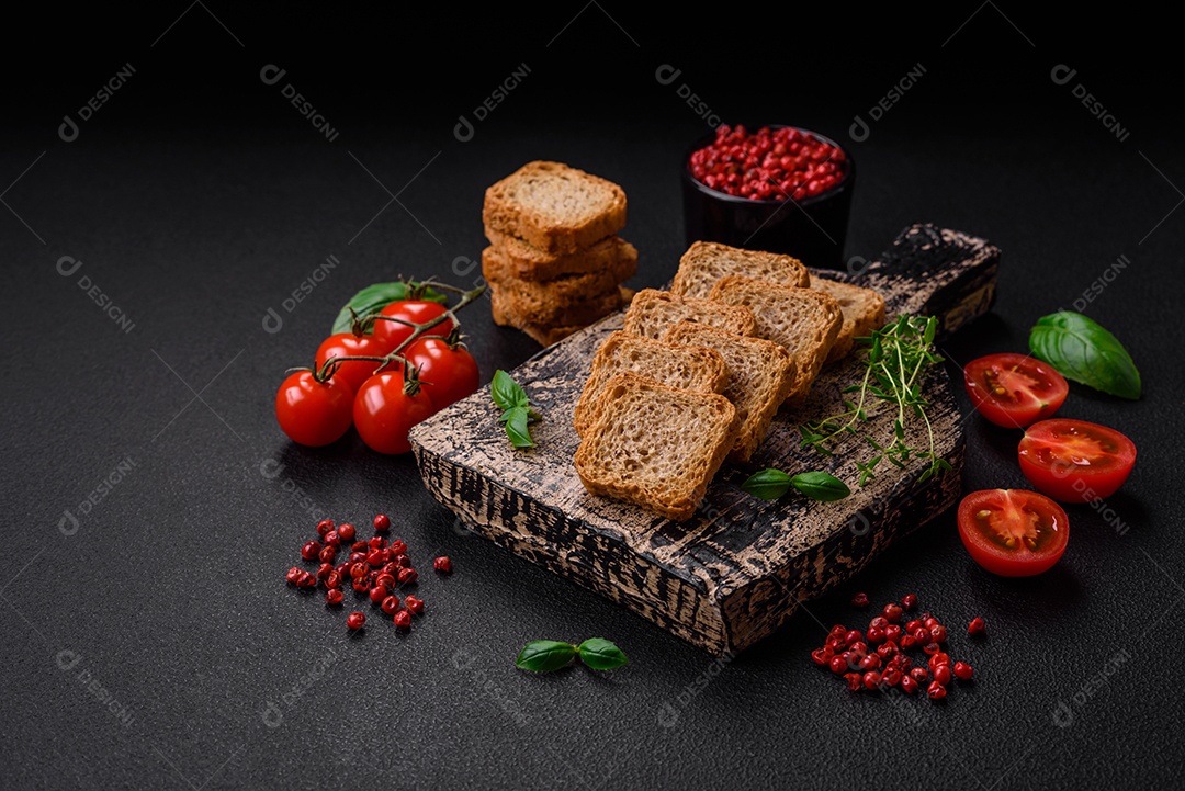 Deliciosos croutons de trigo retangulares salgados com sal e especiarias sobre um fundo escuro de concreto