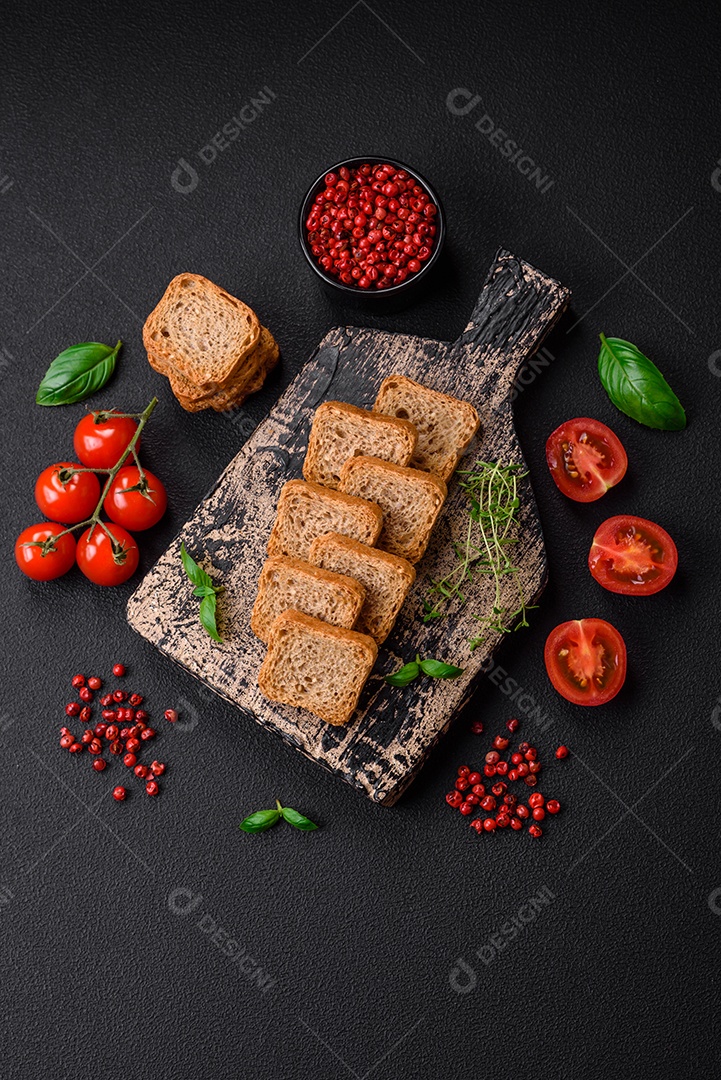 Deliciosos croutons de trigo retangulares salgados com sal e especiarias sobre um fundo escuro de concreto
