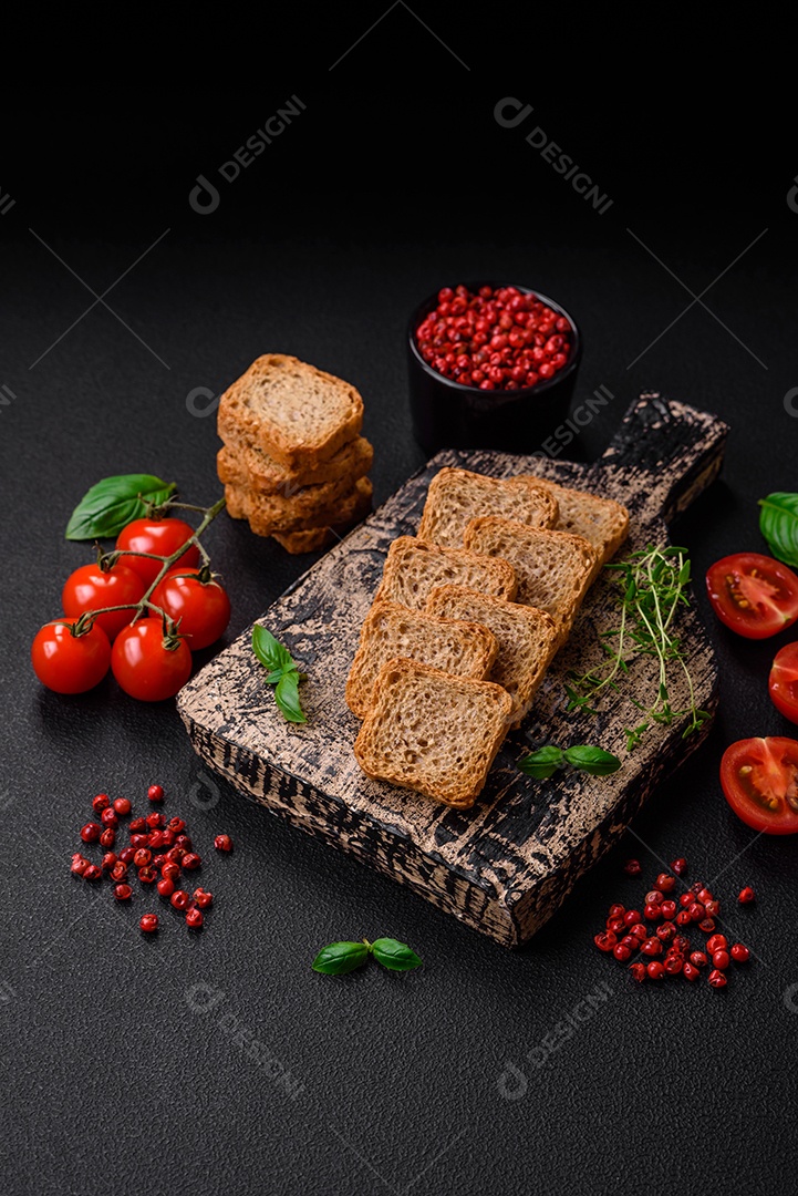 Deliciosos croutons de trigo retangulares salgados com sal e especiarias sobre um fundo escuro de concreto