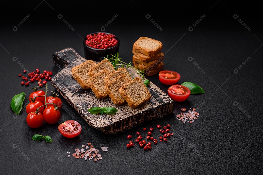 Deliciosos croutons de trigo retangulares salgados com sal e especiarias sobre um fundo escuro de concreto