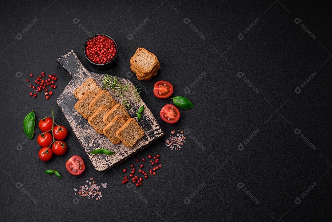 Deliciosos croutons de trigo retangulares salgados com sal e especiarias sobre um fundo escuro de concreto