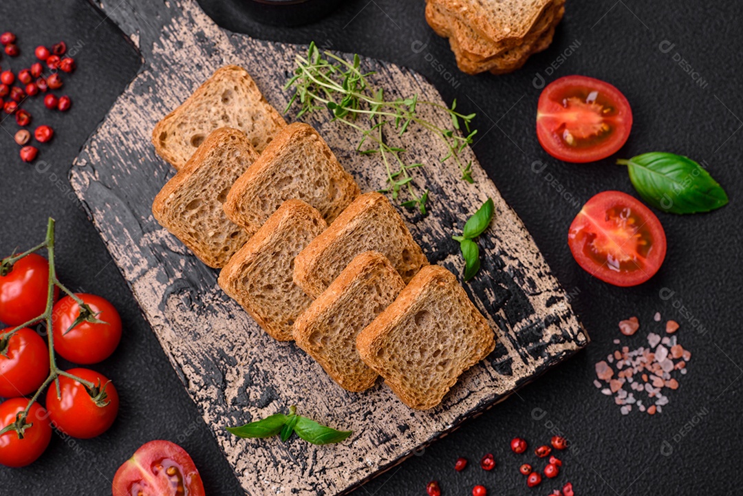 Deliciosos croutons de trigo retangulares salgados com sal e especiarias sobre um fundo escuro de concreto