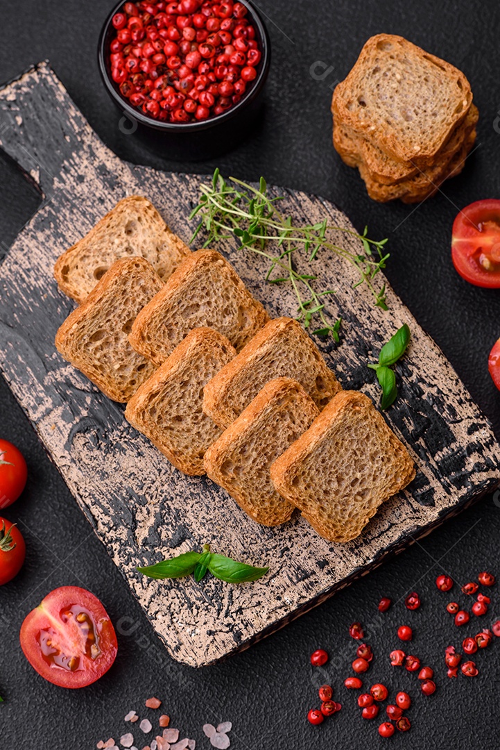 Deliciosos croutons de trigo retangulares salgados com sal e especiarias sobre um fundo escuro de concreto