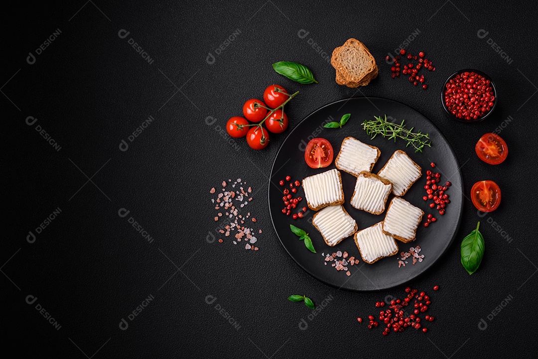 Deliciosos croutons de trigo retangulares salgados com cream cheese, tomate, sal e especiarias sobre um fundo escuro de concreto