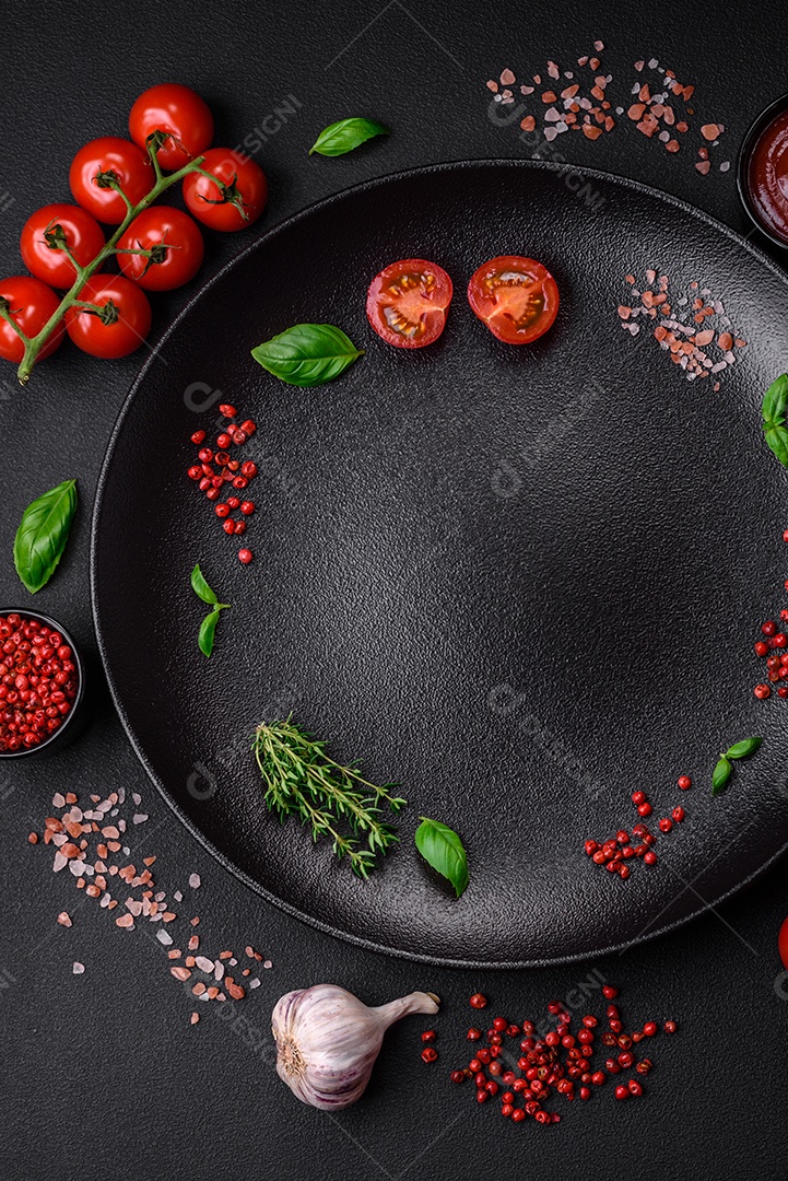 Ingredientes para cozinhar tomate cereja, sal, especiarias e ervas sobre um fundo escuro de concreto